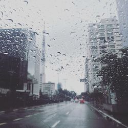 Road seen through wet window in rainy season