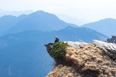 Man standing on rock against sky