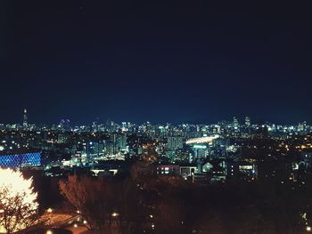 Illuminated cityscape against clear sky at night