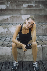 Portrait of smiling young woman with head in hand sitting on steps