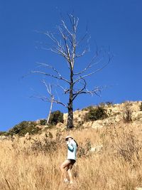 Full length of woman standing by bare tree against sky