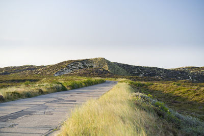 Road leading towards mountains against clear sky