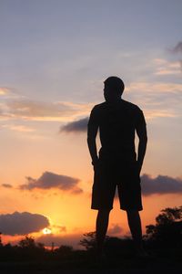 Silhouette man standing on field against sky during sunset