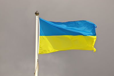 Ukraine ukrainian national flag waving in wind against cloudy gray sky.