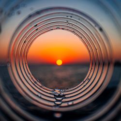 Sea seen through bottle against sky during sunset