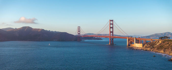 Suspension bridge over river against sky during sunset