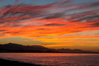 Scenic view of sea against dramatic sky during sunset