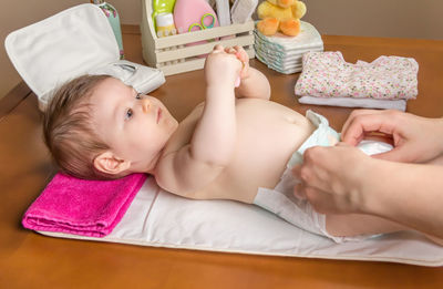 Woman changing diaper of baby girl at home