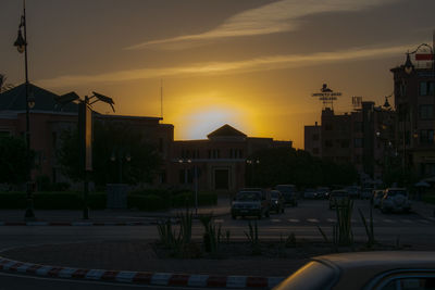 Cars on road against sky during sunset