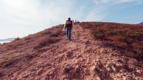 Rear view of man standing on land against sky