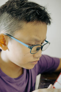 Portrait of young boy wearing glasses looking down at home. low angle view.