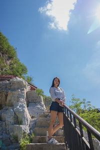 Woman standing by railing against sky