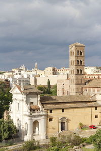 Buildings in city against cloudy sky