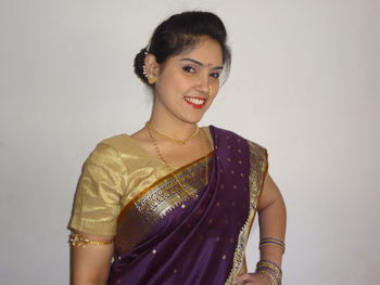 Portrait of smiling woman in sari standing against wall