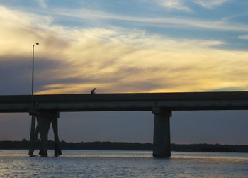 Bridge over river against cloudy sky