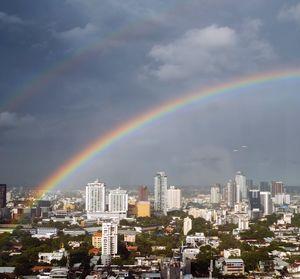 Rainbow over buildings in city against sky