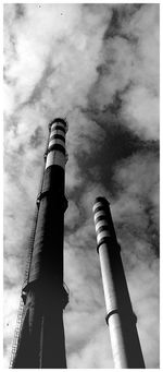 Low angle view of factory against cloudy sky