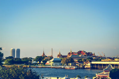 River in city against clear blue sky