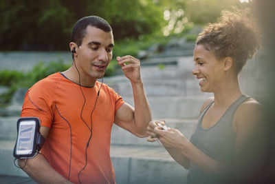 Man hearing music with headphones while woman smiling at steps