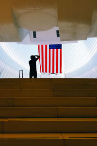 Rear view of silhouette man standing by american flag