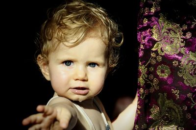 Portrait of cute baby girl standing near fabric