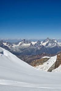 Scenic view of snowcapped mountains against blue sky