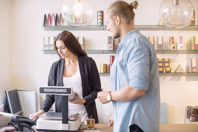 Female worker with colleague discussing while holding product in candy store