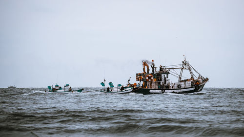 People fishing in sea against clear sky