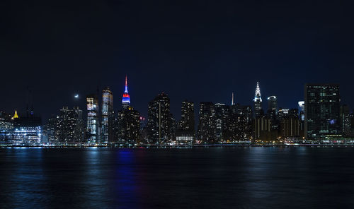 Illuminated cityscape at waterfront during night