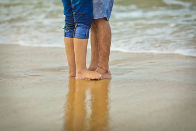 Low section of man standing on beach