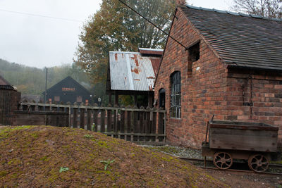 Old house by building against sky