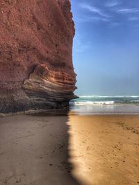 Rock formation on beach against sky