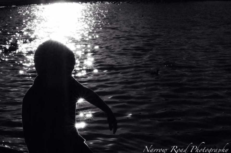 REAR VIEW OF WOMAN STANDING IN SEA