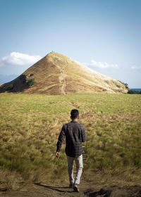 Rear view of man on field against sky