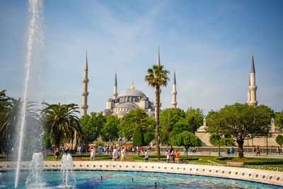 Fountain in front of mosque against sky