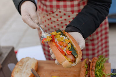 Midsection of man preparing hot dog at home