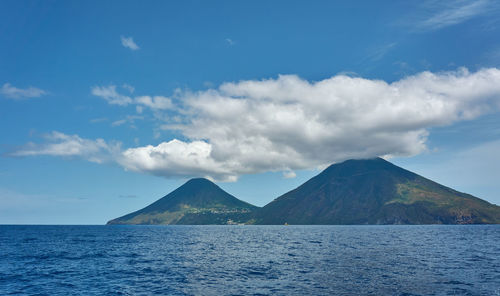 Scenic view of sea and mountains against blue sky