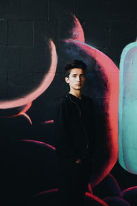 Portrait of young man standing against wall
