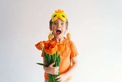 Funny boy with orange tulips and in the mask of a chick on white background.