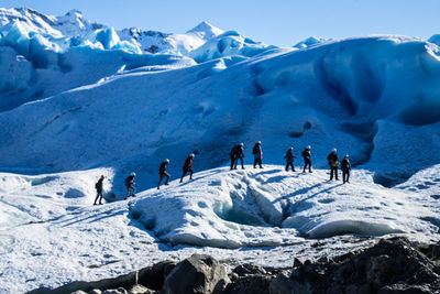 People on snowcapped mountains against sky