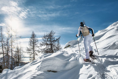 Rear view of woman skiing on snow covered landscape