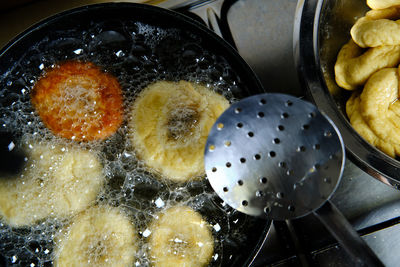 From above bunch of delicious doughnuts frying in hot bubbling oil on stove in kitchen