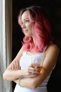 Side view of woman holding coffee cup standing by window