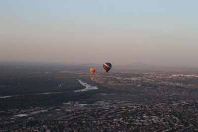 Hot air balloons flying over landscape against sky