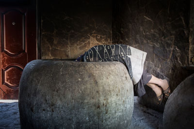 Midsection of person on sofa against rock