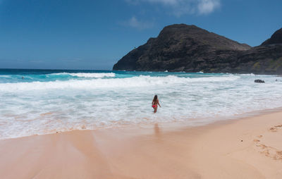 Rear view of woman walking on beach