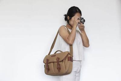 Woman photographing with camera against white background