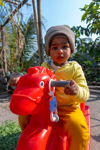 Portrait of cute boy wearing knit hat sitting on toy outdoors