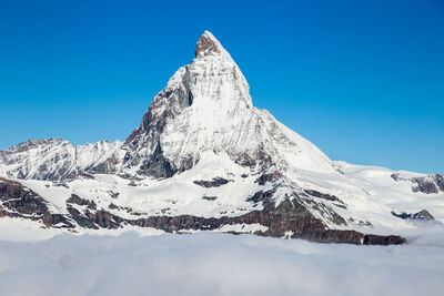 Scenic view of snowcapped mountains against clear blue sky