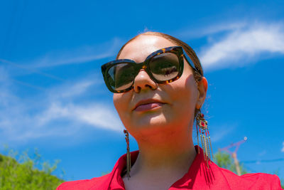 Low angle view of woman wearing sunglasses against blue sky